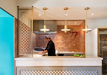 An open modern design tandoor kitchen allows guests to see chefs preparing traditional bread.